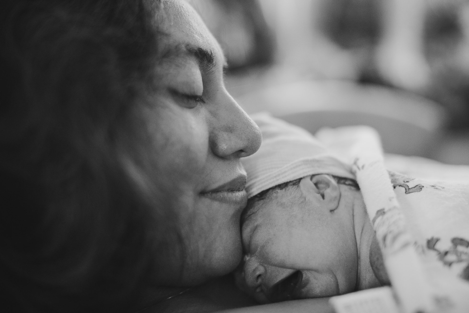 Mom and newborn baby in hospital bed bonding together